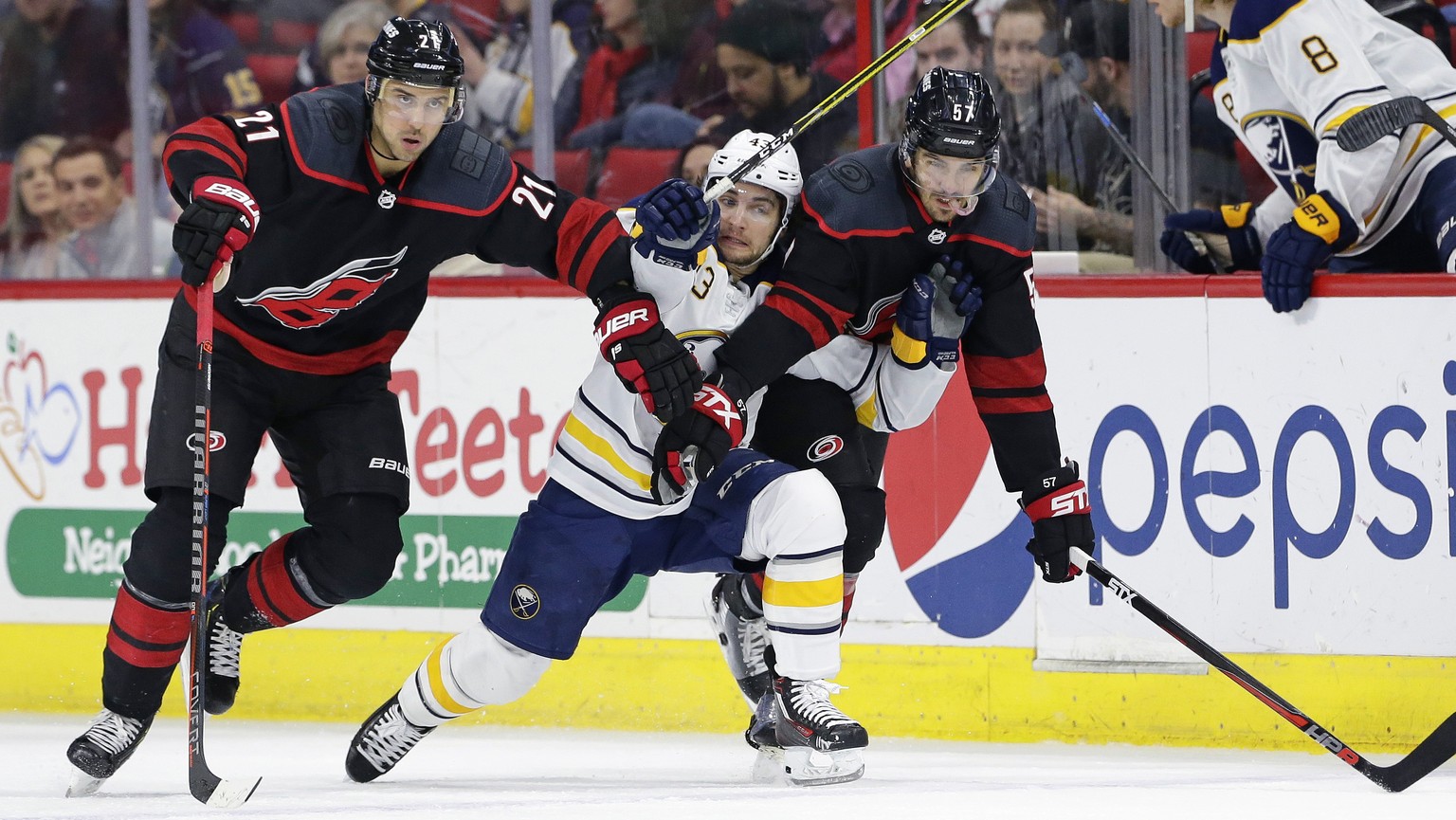 Carolina Hurricanes&#039; Nino Niederreiter (21), of the Czech Republic, and Trevor van Riemsdyk (57) chase the puck with Buffalo Sabres&#039; Conor Sheary during the first period of an NHL hockey gam ...