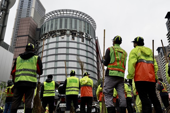 epa11892171 Cleaning workers look towards a damaged department store following a suspected gas explosion, in Taichung city, Taiwan, 13 February 2025. At least four people died and several were injured ...