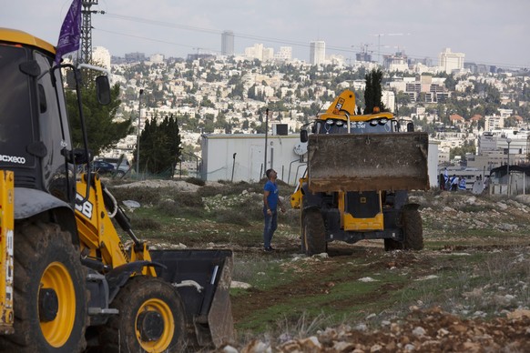 FILE - In this Nov. 16, 2020 file photo, workers take a break before European Union officials visit the construction site for the Givat Hamatos Israeli settlement, in Jerusalem. A West Bank settlement ...