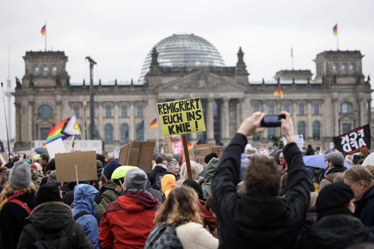 epa11123015 Participants holding placards, one reading 'remigrate you in your knee' (C), take part in a demonstration against a swing to the political right and right-wing extremism in front ...