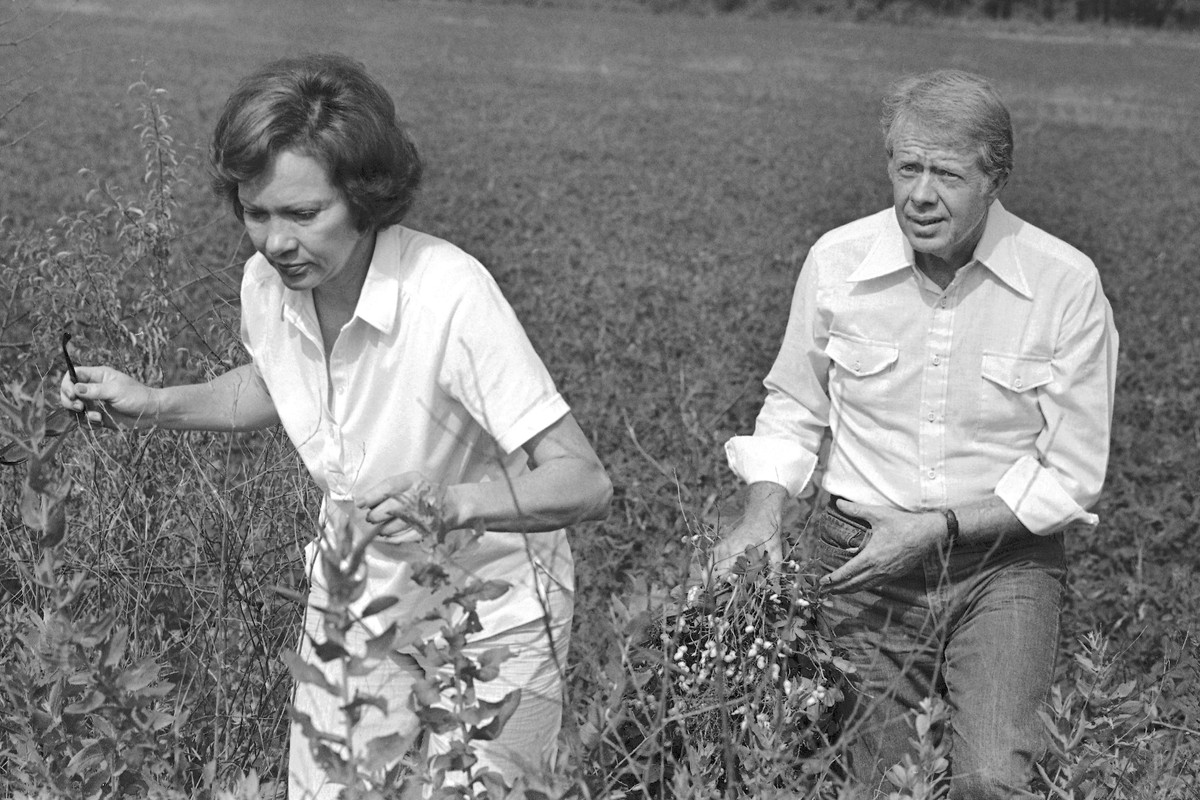 FILE - President Jimmy Carter carries a peanut plant as he follows his wife Rosalynn from the field at their Webster County, Ga., farm on August 19, 1978. (AP Photo/Jim Wells, File)