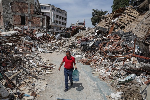 epa10608814 Samir, member of the Greek Orthodox community in Antakya, carries water for the cats in Hatay, Turkey, 04 May 2023. More than 50,000 people died and thousands more were injured after major ...