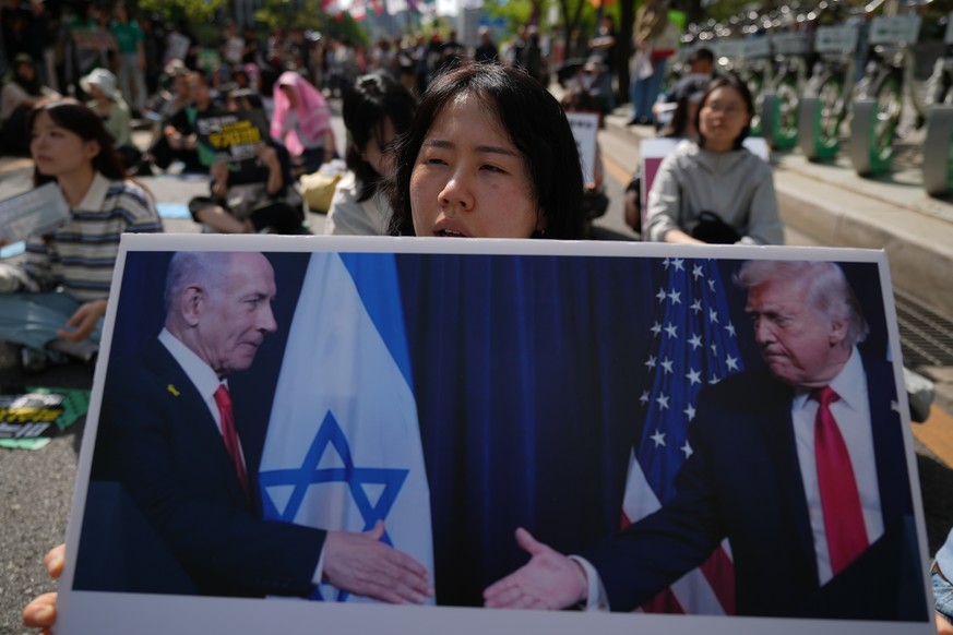 A protester holds a banner showing U.S. President Donald Trump and Israeli Prime Minister Benjamin Netanyahu during a rally denouncing the U.S. and Israel in Seoul, South Korea, Saturday, April 18, 20 ...