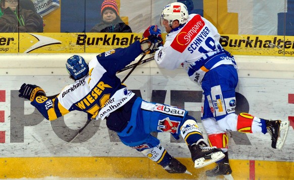 Der Zuercher Daniel Schnyder, rechts, checkt den Davoser Dino Wieser, links, hart beim Eishockey Meisterschaftsspiel der National League A zwischen dem HC Davos und den ZSC Lions am Freitag, 23. Novem ...