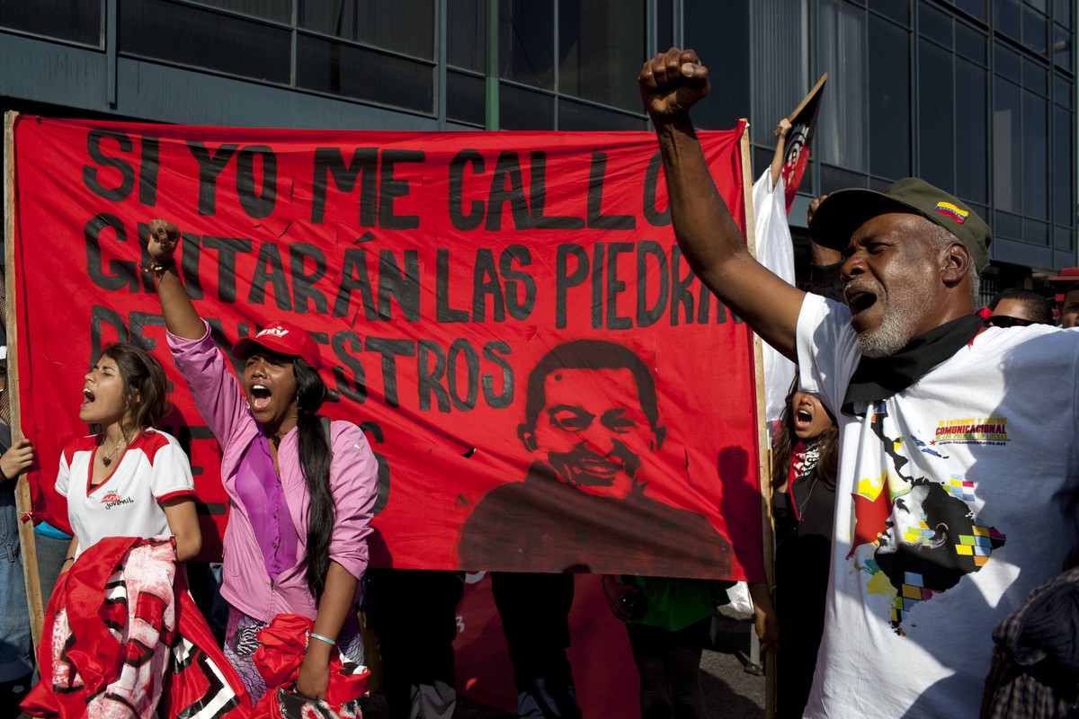Members of a pro-government "colectivo," or "collective," march with a banner of Venezuela's late President Hugo Chavez through downtown Caracas, Venezuela, Thursday, Feb. 20, ...