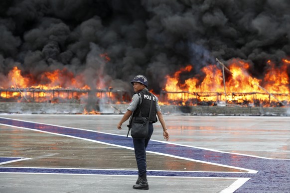 epaselect epa10034510 A policeman walks past a burning pile of illegal drugs during a &#039;Destruction Ceremony of Seized Narcotic Drugs&#039; held to mark the International Day Against Drug Abuse an ...