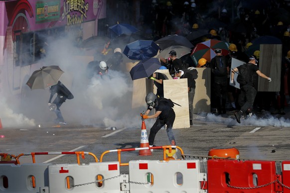 Protesters use traffic cones to cover the tear gas fired by riot police as they face off near the Legislative Council building and the Central Government building in Hong Kong, Monday, Aug. 5, 2019. D ...