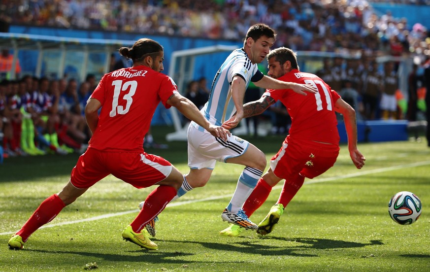 Lionel Messi,from Argentina, carries the ball against Switzerland s Valon Behrami (right ) and Ricardo Rodriguez (left), during a match for the 8t hs. final of the football World Cup Brazil 2014, at C ...