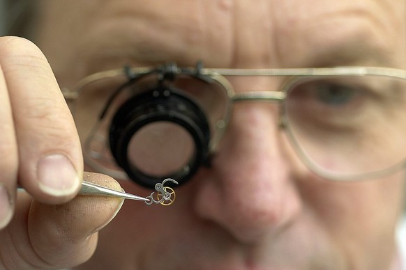 Un horloger de la firme Patek Philippe travaille sur un tourbillon de montre, lors du reportage a la manufacture horlogere Patek Philippe de Plan-les-Ouates Geneve, ce 11 novembre 2005. (KEYSTONE/Sand ...