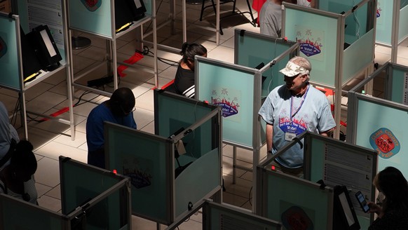 FILE - An election worker walks through voting booths to help as people vote at a polling place June 14, 2022, in Las Vegas. Voting could feel different in this year&#039;s midterms, as the election f ...