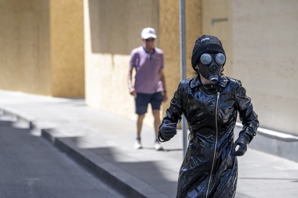 A person poses wearing a gas mask in the streets covered wooden panels installed to protect the facade ahead of demonstrations against the G7 summit in nearby Evian, in Geneva, Switzerland, Saturday,  ...