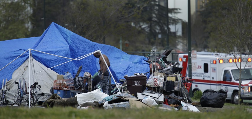 In this file photo from Thursday, March 19, 2020, an ambulance drives by a homeless encampment in Oakland, Calif. Efforts to move California&#039;s large homeless population into isolated quarters to  ...