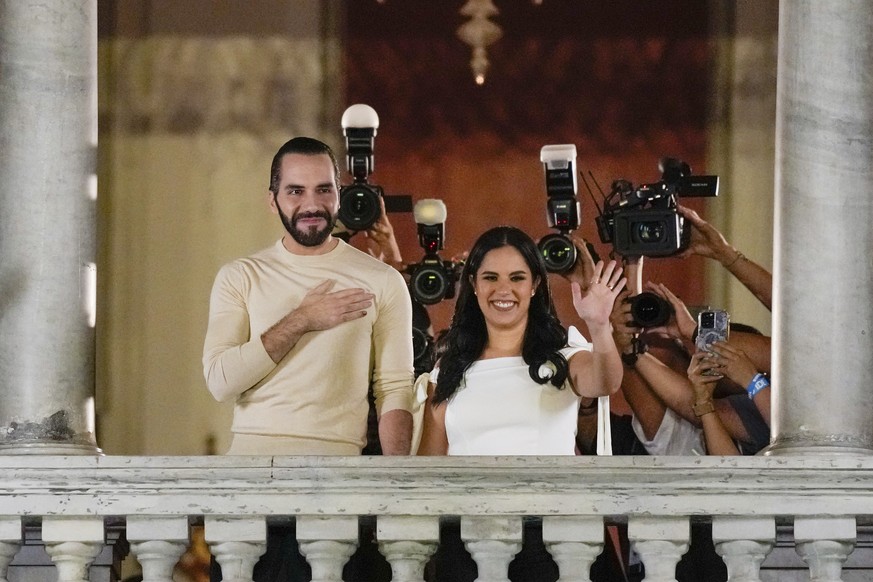 El Salvador President Nayib Bukele, left, accompanied by his wife Gabriela Rodriguez, wave to supporters from the balcony of the presidential palace in San Salvador, El Salvador, after polls closed fo ...