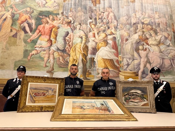 In this picture made available by the Italian Carabinieri in Parma, northern Italy, Friday, Aug. 14, 2026, Carabinieri pose near three paintings recovered following a police operation: "Tasse et  ...