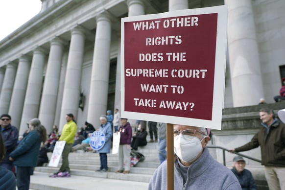 FILE - A person holds a sign referencing the U.S. Supreme Court as they take part in a rally in favor of abortion rights on the steps of the Temple of Justice, which houses the Washington state Suprem ...