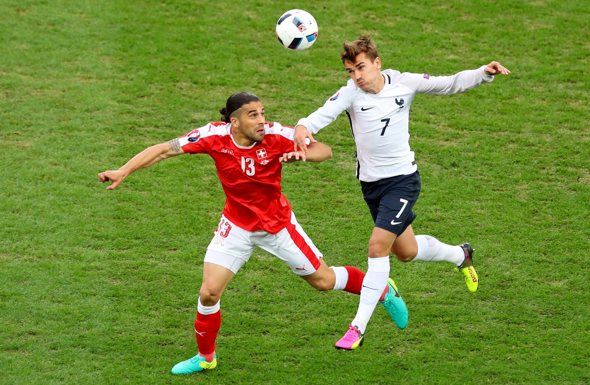 Switzerland's Ricardo Rodriguez jumps for the ball next to France's Antoine Griezmann during the Euro 2016 Group A soccer match between Switzerland and France at the Pierre Mauroy stadium in ...