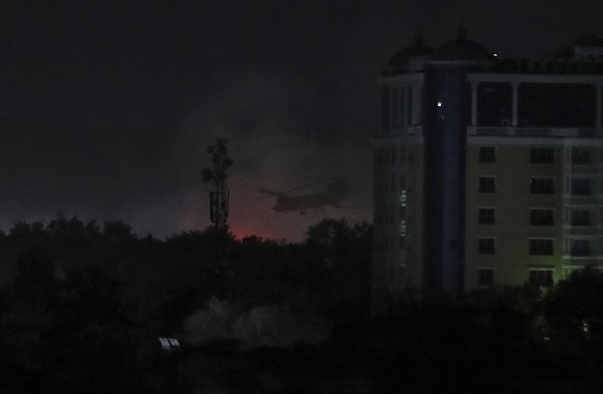 A U.S. Chinook helicopter flies near the U.S. Embassy as smoke rises in Kabul, Afghanistan, late Sunday, Aug. 15, 2021. (AP Photo/Rahmat Gul)