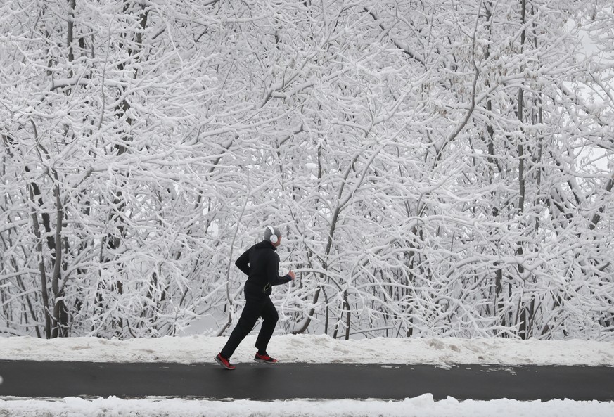 epa09641309 A man jogging through a park after a heavy snowfall in Moscow, Russia 14 December 2021. EPA/YURI KOCHETKOV