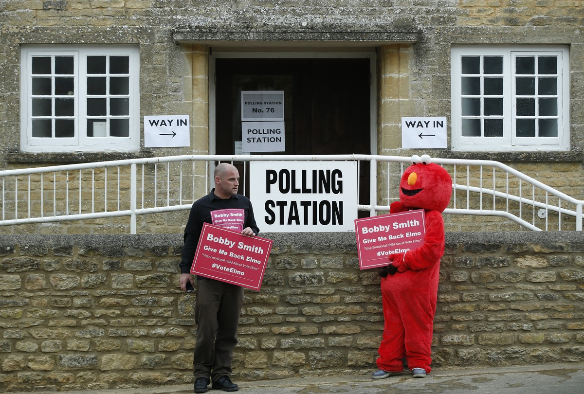 A candidate's supporters parade in front of the polling station where Britain's Prime Minister David Cameron and his wife Samantha will vote in Spelsbury, England, in the general election, T ...