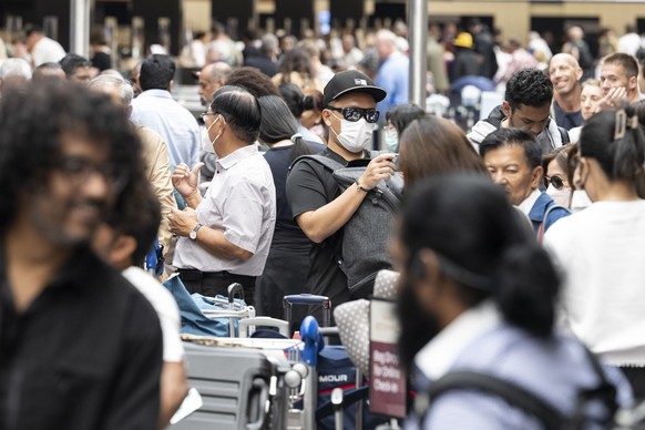 Fluggaeste warten vor einer Anzeigetafel am Mittwoch, 15. Juni 2022, auf dem Flughafen in Zuerich. Wegen einer Informatikpanne von Skyguide sind die Flughaefen Zuerich und Genf derzeit lahmgelegt. Es  ...