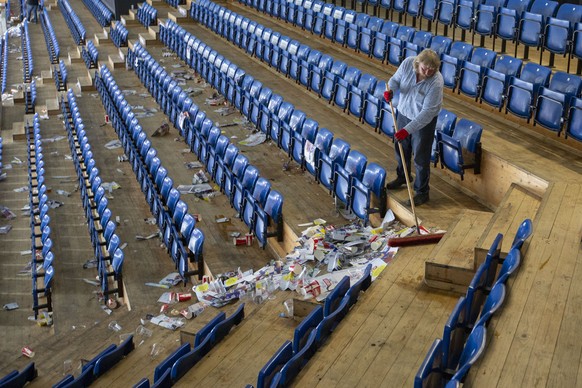 Ein Mann kehrt mit einem Besen den Muell zusammen in den Zuschauerraengen nach dem dritten Eishockey Spiel der Ligaqualifikation der National League zwischen dem EHC Kloten und dem SC Rapperswil-Jona  ...