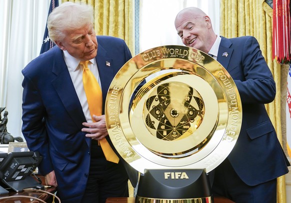 epa11947940 United States President Donald J Trump (L) stands with FIFA President Gianni Infantino and the Club World Cup trophy after signing an Executive Order setting up a task force on the World C ...