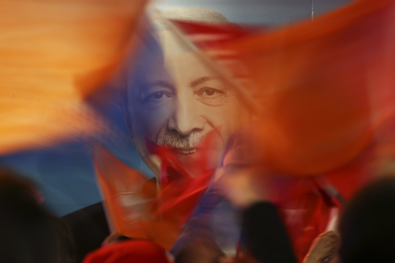 FILE - Supporters of President Recep Tayyip Erdogan wave flags in front of his picture in Istanbul, on March 31, 2019. Turkey is heading toward presidential and parliamentary elections on Sunday May 1 ...