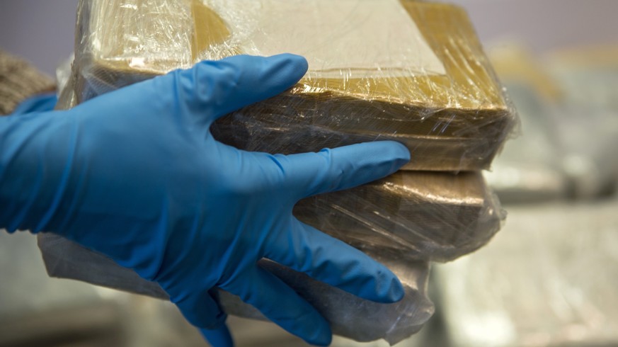 epa05237447 A police officer wearing blue gloves holds seized blocks of cocaine at a press conference in Darmstadt, Germany, 31 March 2016. Searchers with the South Hessian police headquarters uncover ...