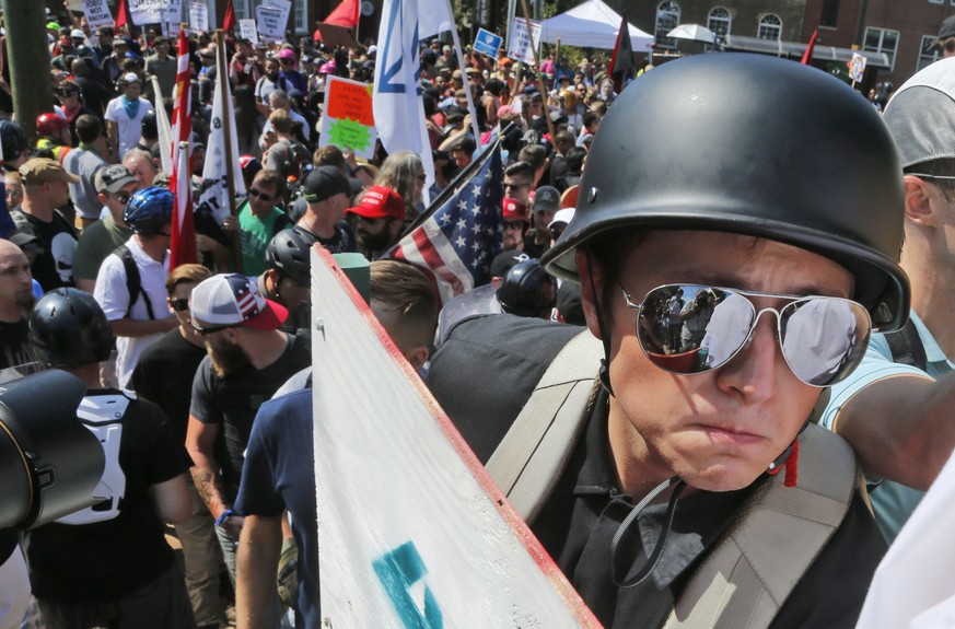 A white nationalist demonstrator with a helmet and shield walks into Lee Park in Charlottesville, Va., Saturday, Aug. 12, 2017. Hundreds of people chanted, threw punches, hurled water bottles and unle ...