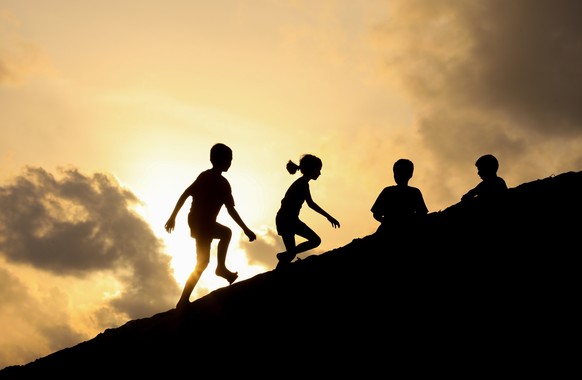 epa08755521 Sri Lankan Children are silhouetted against the evening sky as they play on a beach dune while the sun sets in Colombo, Sri Lanka, 18 October 2020. EPA/CHAMILA KARUNARATHNE