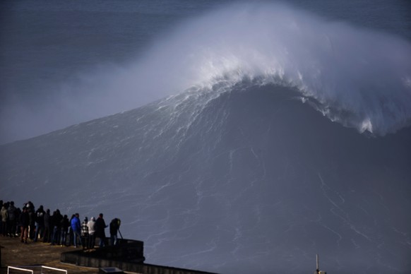 People gather at the lighthouse of the Praia do Norte or North beach, during a tow-in surfing session, in Nazare, Portugal, Thursday, Dec, 11, 2014. The beach has become a famous break point for big w ...