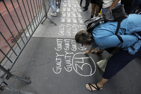 epa11380837 A woman writes the words &#039;guilty&#039; 34 times in chalk on the sidewalk across the street from Trump Tower after a jury found former US President Donald Trump guilty on all 34 counts ...