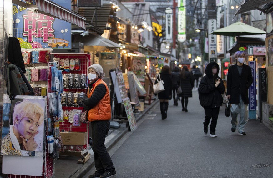 A sales person wearing a face mask stands outside as people walk on a street in a neighborhood dubbed &quot;Korea Town&quot; where businesses from Asian countries mainly from South Korea are situated  ...