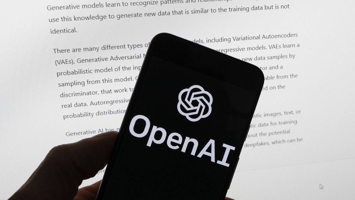 FILE - The OpenAI logo is seen on a mobile phone in front of a computer screen displaying output from ChatGPT, March 21, 2023, in Boston. Digital news outlets The Intercept, Raw Story and AlterNet are ...