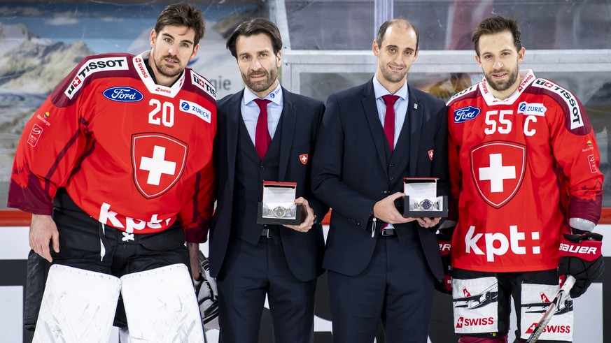 Switzerland&#039;s goalkeeper Reto Berra, left, Switzerland&#039;s defender Romain Loeffel, right, pose with Lars Weibel, director of national teams and Patrick Bloch, CEO of Swiss Ice Hockey Federati ...