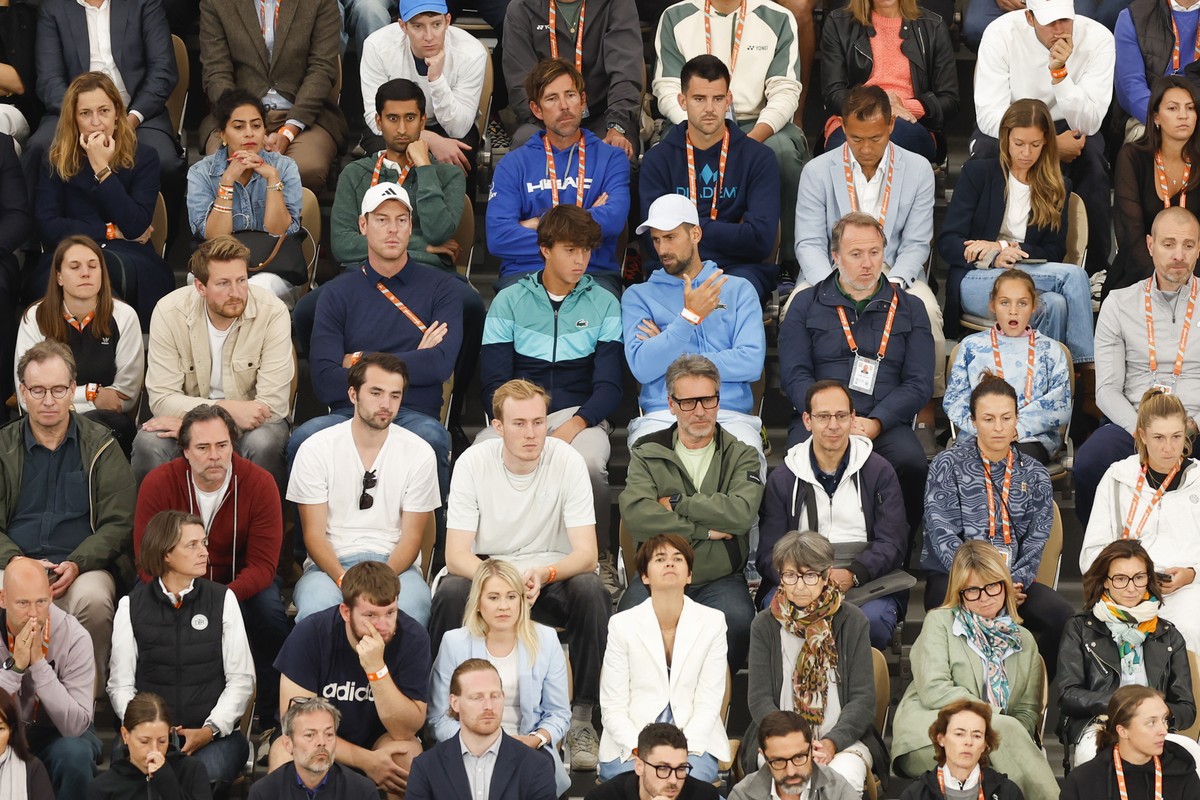 Serbia's Novak Djokovic, center right with blue sweater and white cap, watches Spain's Rafael Nadal's first round match of the French Open tennis tournament against Germany's Alexa ...