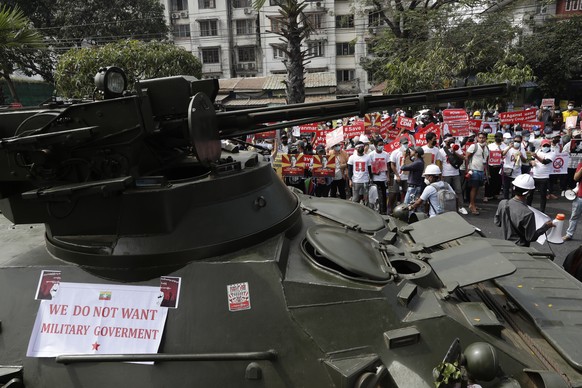 epa09014258 Demonstrators gather near a road where soldiers and armored vehicles are deployed during a protest outside the Central Bank of Myanmar (CBM) in Yangon, Myanmar, 15 February 2021. Myanmar&# ...