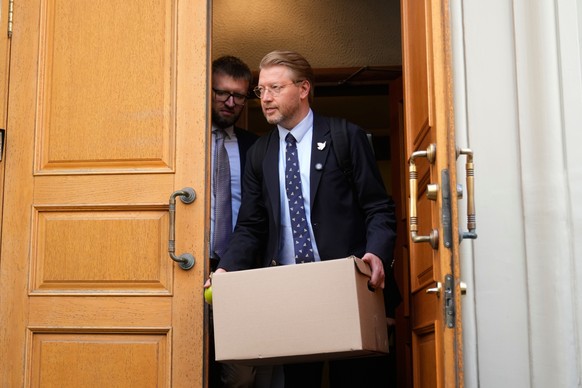 Yabloko party leader Nikolai Rybakov carries a box with documents leaving the Russia's Supreme Court after hearing an appeal on a lawsuit to bar the party from the upcoming parliamentary election ...