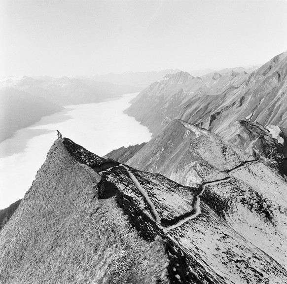 Two hikers standing on a peak of the Brienzergrat look down onto the sea of fog which lies above Lake Brienz, pictured in Brienz, Canton of Berne, Switzerland, on November 10, 1969. The newly built hi ...