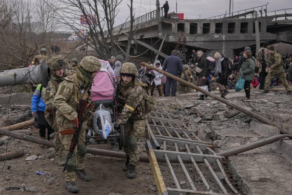 Ukrainian servicemen carry a baby stroller after crossing the Irpin river on an improvised path under a bridge, that was destroyed by Ukrainian troops designed to slow any Russian military advance, wh ...