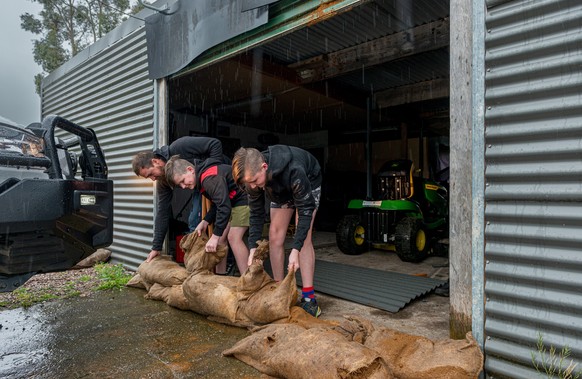 epa10240099 (L-R) Steve, Jack and Tommy Lowery help to sandbag a property in Railton, Tasmania, Australia, 13 October 2022. Heavy rain that began on Wednesday night is expected to continue into Friday ...