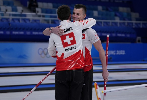 Switzerland&#039;s Valentin Tanner, hugs his teammate Switzerland&#039;s skip Peter De Cruz, after winning the men&#039;s curling match against Canada, at the 2022 Winter Olympics, Friday, Feb. 11, 20 ...