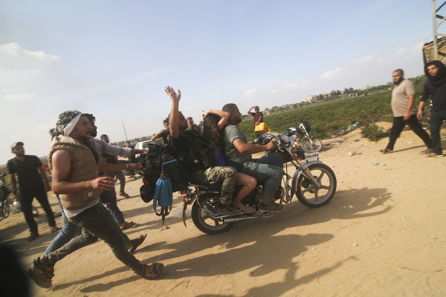 Palestinians transport a captured Israeli civilian, center, from Kfar Azza kibbutz into the Gaza Strip on Saturday, Oct. 7, 2023. The militant Hamas rulers of the Gaza Strip carried out an unprecedent ...
