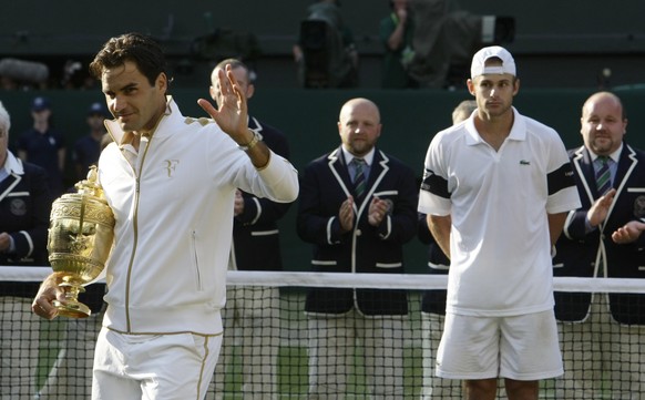 Roger Federer of Switzerland (L) waves as he holds his trophy after defeating Andy Roddick of the U.S. (R) in their Gentlemen&#039;s Singles finals match at the Wimbledon tennis championships in Londo ...