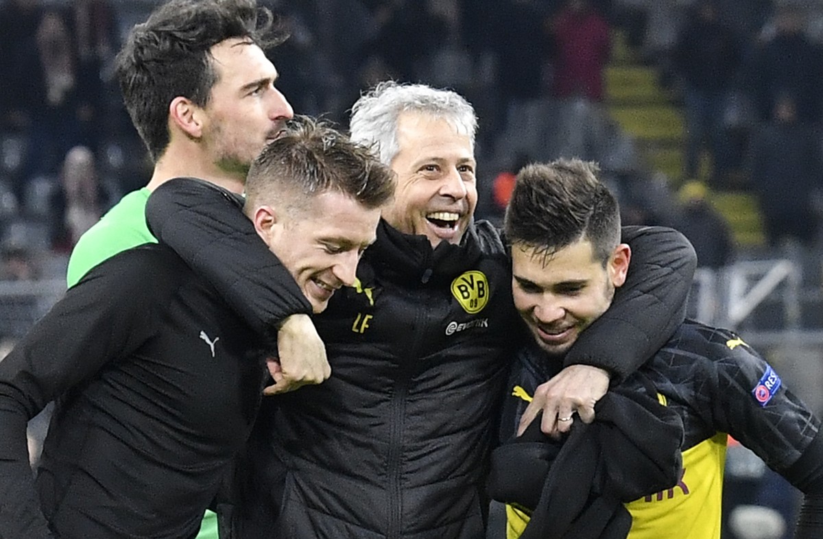 Dortmund's head coach Lucien Favre, center, embraces Dortmund's Marco Reus, left, and Dortmund's Raphael Guerreiro, right, after winning the Champions League Group F soccer match betwee ...