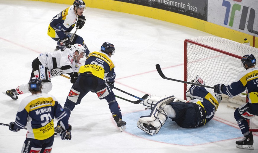 Lugano's player Daniel Carr, Ambri's player Michael Fora and Ambri's goalkeeper Benjamin Conz, from left, fight for the puck, during the preliminary round game of National League Swiss Championship ga ...