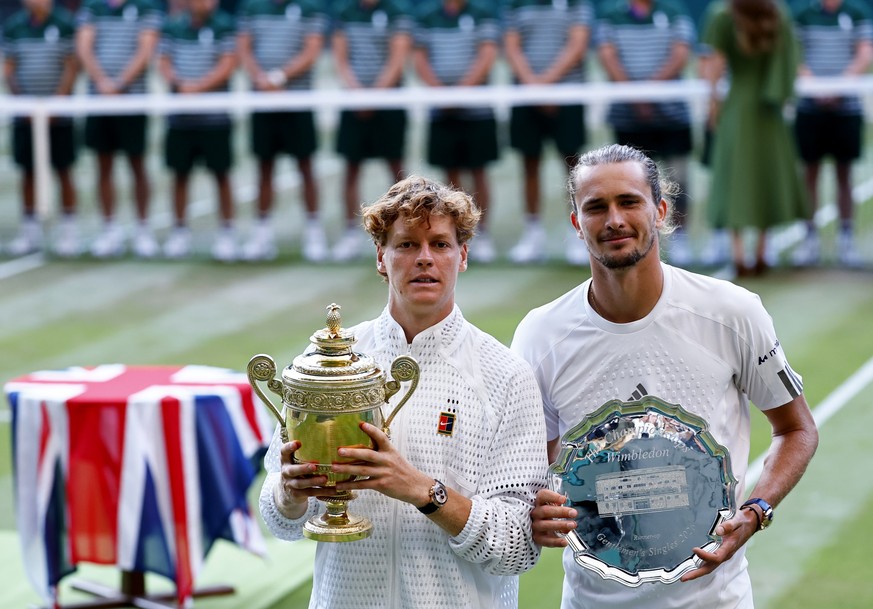 epa13107627 Jannik Sinner of Italy (L) celebrates with the trophy after winning the Men's Singles final against Alexander Zverev of Germany (R), with his runner-up trophy, at the Wimbledon Champi ...