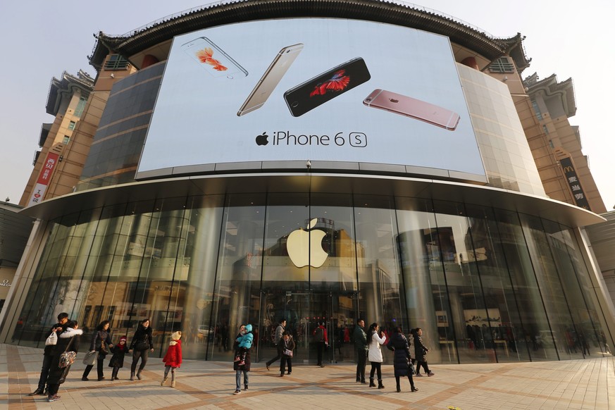 epa05128644 People walk passing by an Apple Store with an iphone 6s advertisement seen on building in Beijing city, China, 27 January 2016. Apple has reported the slowest growth in iPhone sales and wa ...