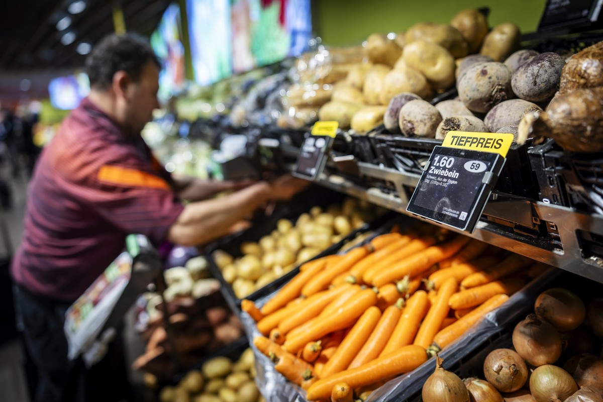Ein Mitarbeiter raeumt Gemuese ein, neben einem Schild mit der Aufschrift "Tiefpreis" in der Migros Limmatplatz, aufgenommen anlaesslich einer Medienkonferenz zu Neuerungen in den Migros-Sup ...