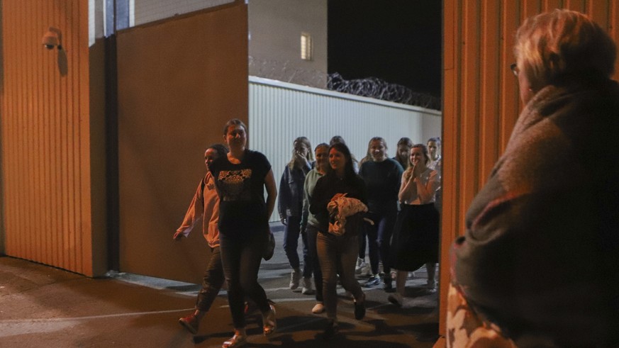 Women walk through a gate after being released from a detention center where protesters were detained during a mass rally following presidential election in Minsk, Belarus, Friday, Aug. 14, 2020. Near ...